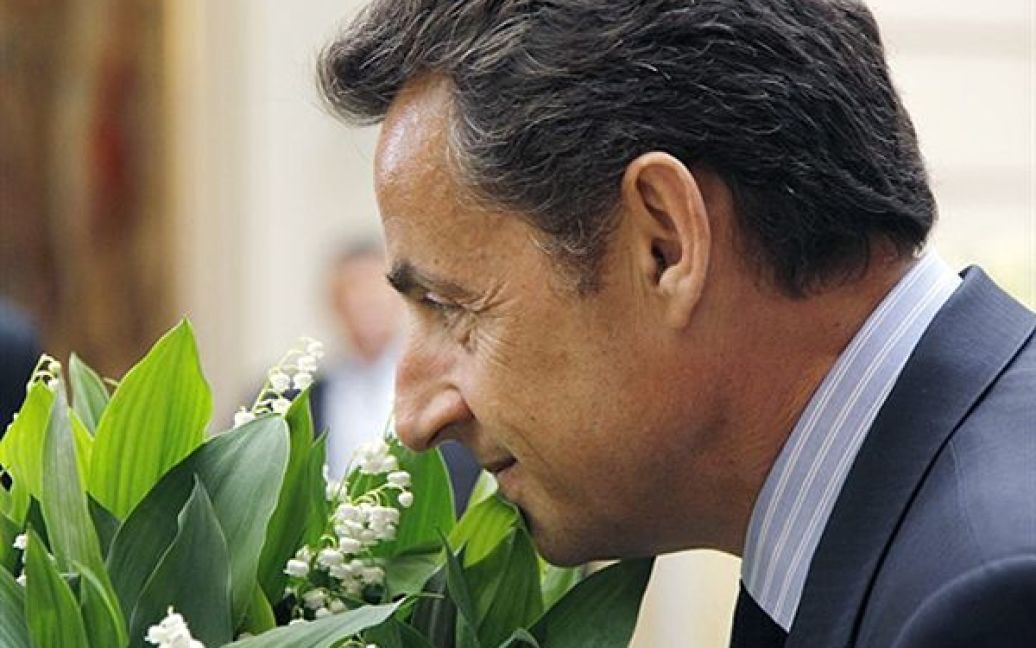 Ніколя Саркозі нюхає букет конвалій під час урочистого прийому у Єлисейському палаці на честь Дня солідарності трудящих. / © AFP
