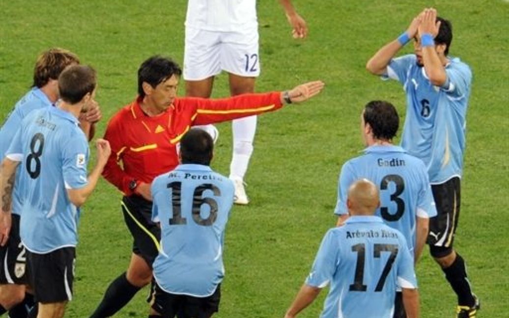 Юічи Нішимура вилучає уругвайського футболіста / © AFP