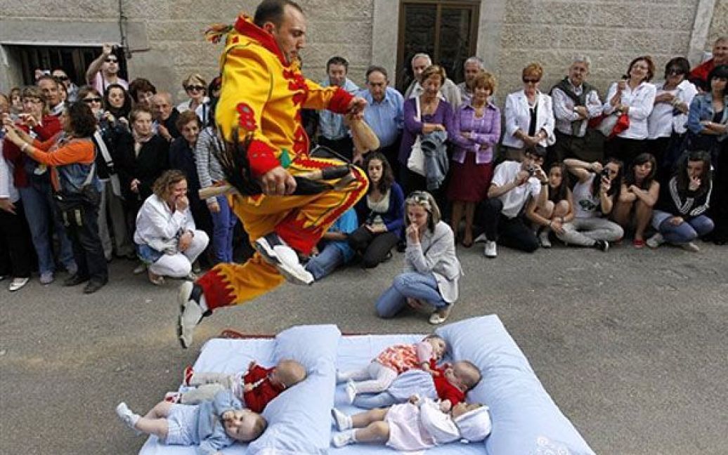 Іспанія, Кастрільо-де-Мурсія. Чоловік у костюмі чорта перестрибує через дітей, які лежать на матраці, під час ритуалу "Ель-Сальто-дель-Колахо" ("Стрибок диявола") з нагоди свята Тіла Христового. / © AFP