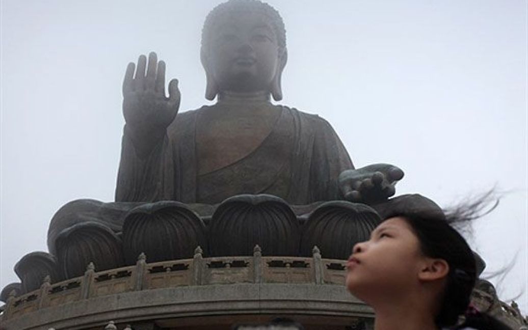 Китай, Гонконг. Дівчинка стоїть перед статуєю Будди Тіан Тан, відомою також як Великий Будда, на острові Лантау у Гонконзі. Буддисти у всьому світі святкують день народження Сіддхартхи Гаутами, духовного вчителя, який заснував буддизм. Гігантська статуя Будди у Гонконгу була до 2007 року найвищою у світі, її висота складає 34 метри. / © AFP
