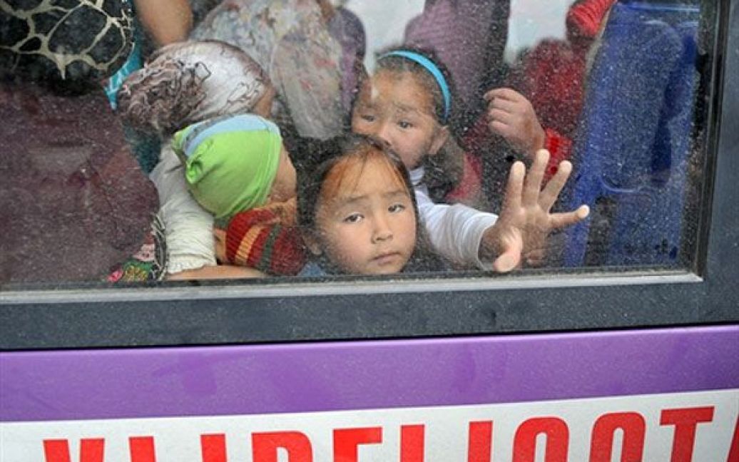 Киргизстан, Ош. Киргизькі діти дивляться з вікна автобуса, доки вони чекають від&#039;їзду до Бішкеку з південного міста Ош. Як мінімум 400 тисяч жителів Киргизії були змушені кинути свої будинки і стати біженцями через безлади на етнічному ґрунті, що пройшли там. Про це повідомила представник Комітету з координації гуманітарних питань ООН Елізабет Бірс. За її словами, тільки в сусідній Узбекистан від погромників і мародерів втекли від 75 до 100 тисяч людей. / © AFP