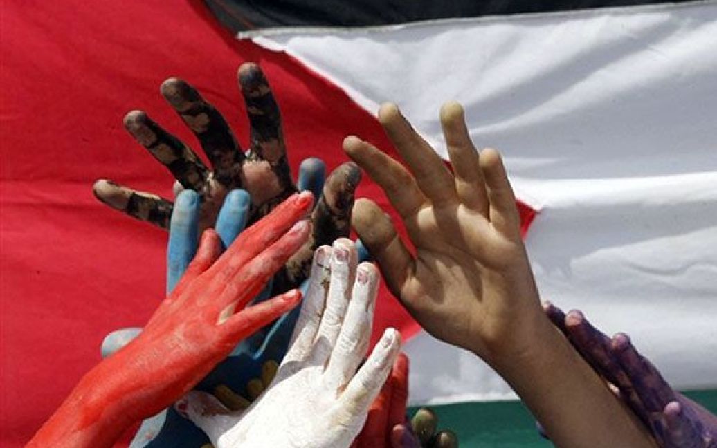 Ліван, Сідон. Ліванські студенти пофарбували руки в різні кольори, що символізує різні національності активістів "Флотилії свободи", які були вбиті або поранені у секторі Газа 31 травня. Студенти зібрались під величезним палестинським прапором під час акції протесту у місті Сідон. / © AFP