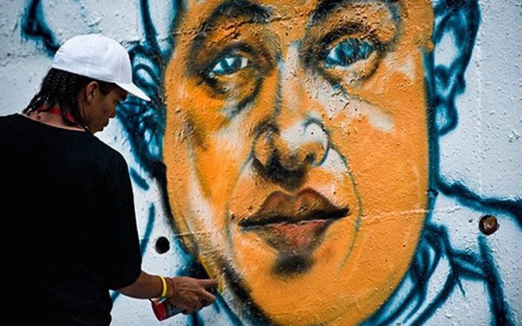 Венесуела, Каракас. Вуличний художник Вільдемар Льєндо малює графітті із зображенням президента Венесуели Уго Чавеса на стіні на одній з головних вулиць Каракаса. / © AFP