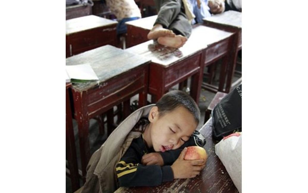 Родини, які були евакуйовані з долини ріки Фу через повінь, сплять у класній кімнаті однієї зі шкіл Фучжоу. Китайським рятувальникам довелося евакуювати більше 120 тисяч людей через прорив дамби на ріці Фу. Повінь у Китаї вже забрала життя 200 людей. / © AFP