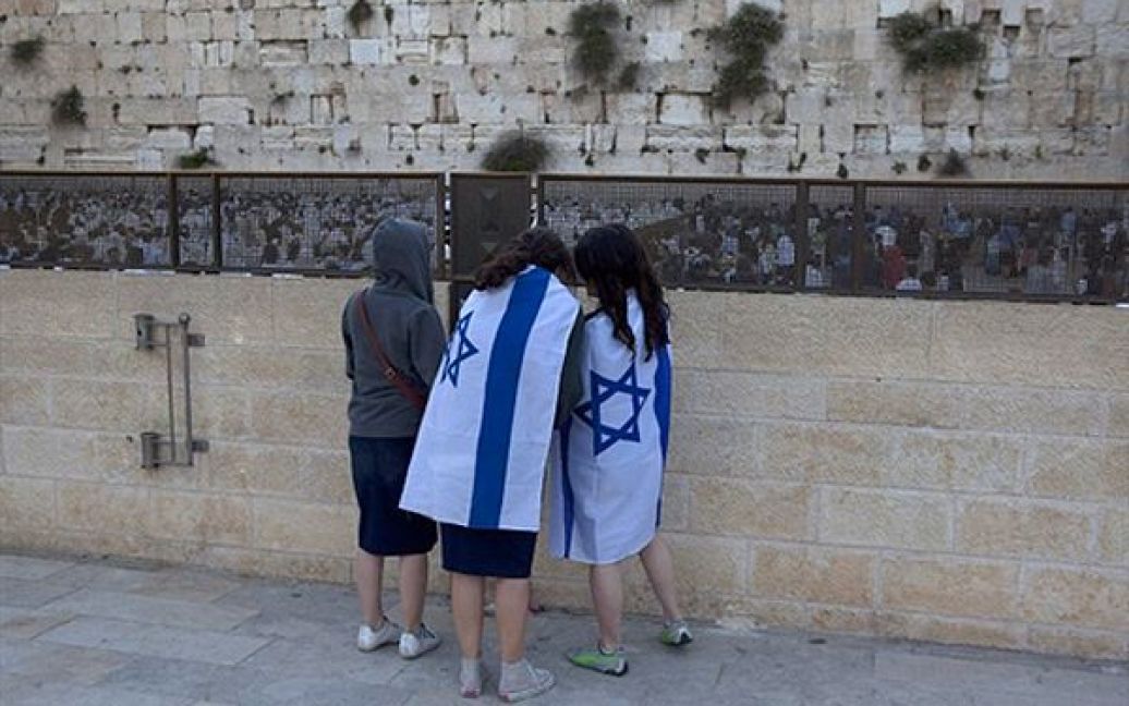 Молоді ізраїльтянки, загорнуті у національний прапор, моляться у Стіни Плачу в Єрусалимі. Ізраїль відмічає об&rsquo;єднання з Єрусалимом після 6-денної війни 1967 року. / © AFP