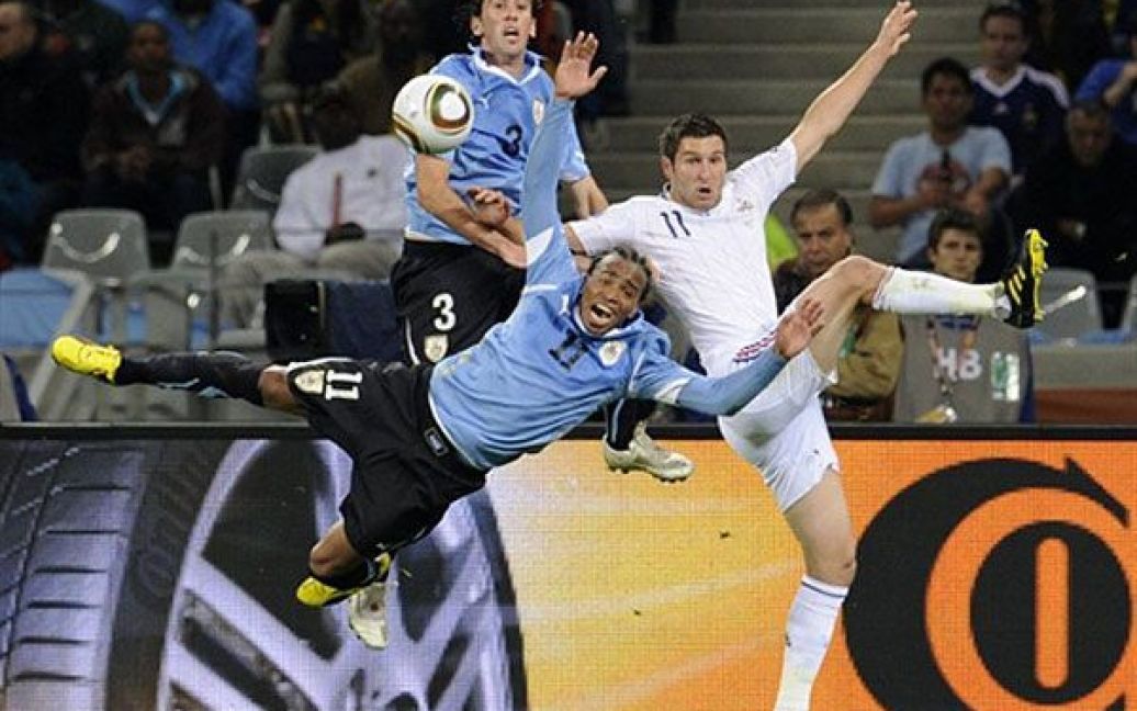 Південна Африка, Кейптаун. Нападаючий збірної Франції Андре-П&#039;єр Жиньяк (праворуч) бореться за м&#039;яч із півзахисником збірної Уругваю Альваро Перейра і захисником Дієго Годіном під час відбіркового матчу Чемпіонату світу з футболу 2010 на стадіоні у Кейптауні. Матч закінчився внічию. / © AFP
