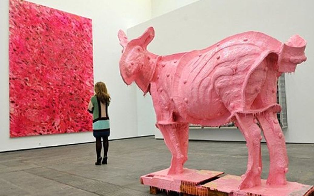 Відвідувачка роздивляється картину Деміена Херста "Рак жирових клітин", а поза нею стоїть скульптура Майкла Джу "Двійник (Рожевий Росіната)" під час прес-відкриття спільної виставки Херста та Джу у Берліні. / © AFP