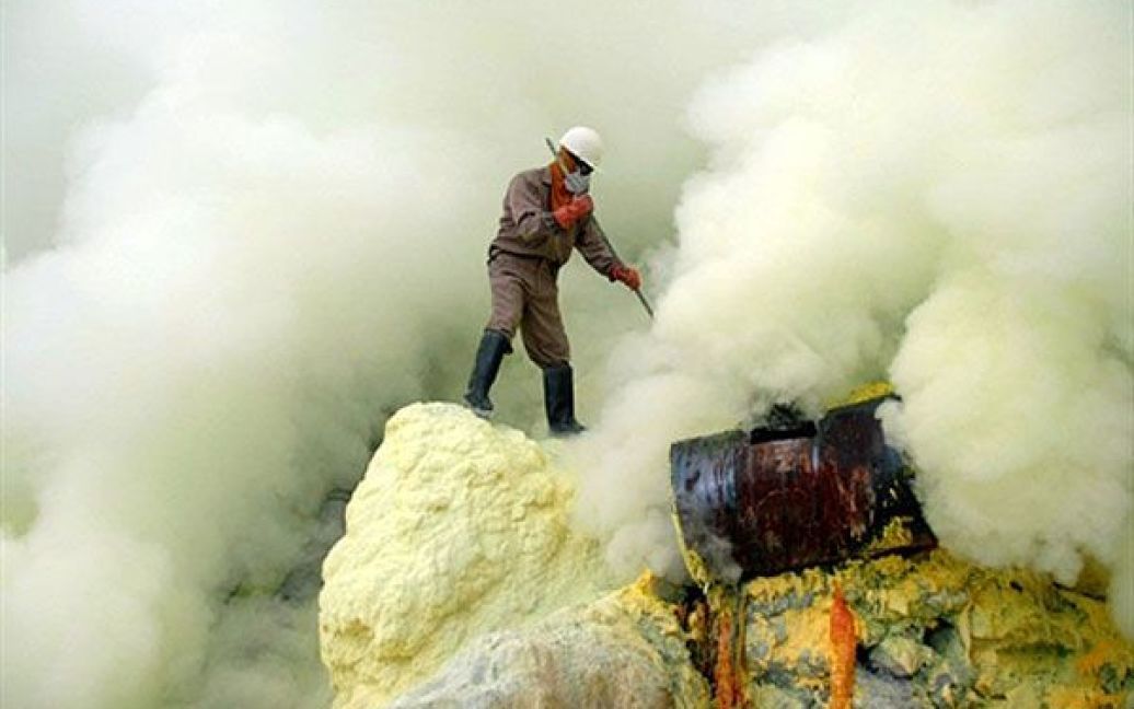 Індонезія. Шахтар, який працює на видобутку сірки на кратері Іджен, оточений отруйним димом. Щодня індонезійські працівники сірчаних шахт переносять до 70 кілограмів отруйної породи у блоках, за що отримують лише від 70 000 до 80 000 рупій (7 - 8 доларів США) на день. / © AFP