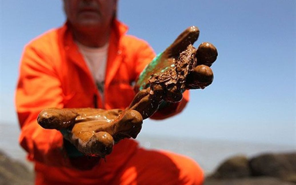 США. Член "Грінпісу", морський біолог Пол Хорсман показує нафту, зібрану в гирлі річки Міссісіпі у штаті Луїзіана. Компанія "BP" сьогодні оголосила, що їм вдається щодня відкачувати до 1000 барелів нафти з глибоководної платформи, яка вибухнула і затонула у Мексиканській затоці 22 квітня. / © AFP