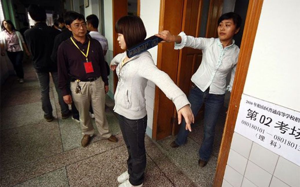 Китай, Суйнінь. Вчителька перевіряє учнів на наявність електронних пристроїв перед щорічними вступними іспитами "гаокао". Більше 10 мільйонів абітурієнтів у Китаї цього року складають вступні іспити іспити. / © 