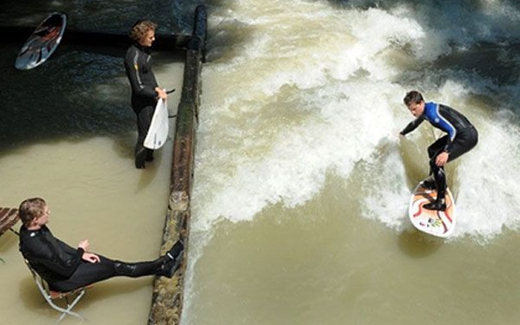 Німеччина, Мюнхен. Серфер катається на хвилях каналу "Eisbach" у Англійському саду (Мюнхен). Температура у Баварії піднялась до 26 градусів за Цельсієм. / © AFP