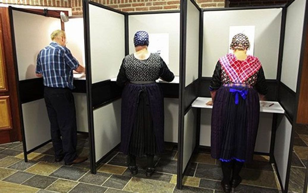 Нідерланди, Степхорст. Жінки у традиційних національних сукнях голосують на загальних виборах. У Голландії відбулись вибори до нового парламенту. Право-центристська партія перед виборами пообіцяла населенню не скорочувати державні витрати, отже відверто антиіммігрантська партія поки лідирує на виборах. / © AFP