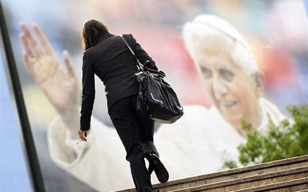Португалія, Лісабон. Жінка проходить поруч із плакатом, на якому зображено Папу Римського Бенедикта XVI, напередодні офіційного візиту Папи Бенедикта XVI до Португалії. / © AFP