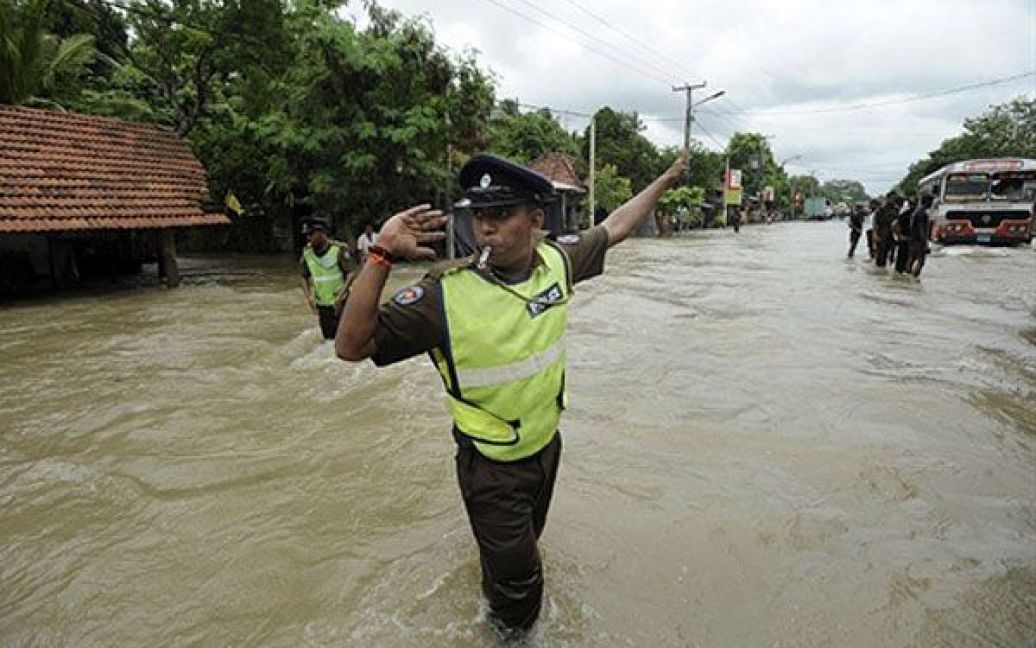 Шрі-Ланки, Коломбо. Поліцейський регулює дорожній рух на затопленій вулиці у передмісті Коломбо. Сильні мусонні дощі, які не вщухали протягом 4 днів, спричинили повінь у країні. В результаті розгулу стихії загинуло 17 людей, більше 400 тисяч були змушені залишити свої домівки. Найбільше постраждала від мусону столиця Шрі-Ланки Коломбо, водою розмило під&#039;їзні шляхи до аеропорту. / © AFP