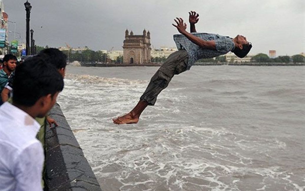 Індія, Мумбаї. Індійський хлопчик стрибає у воду. Щорічні мусони в Індії мають вирішальне значення для фермерів і зростання національної економіки. У Мумбаї сподівання на сильні дощі виправдались, і цього тижня спеку змінили зливи. / © AFP