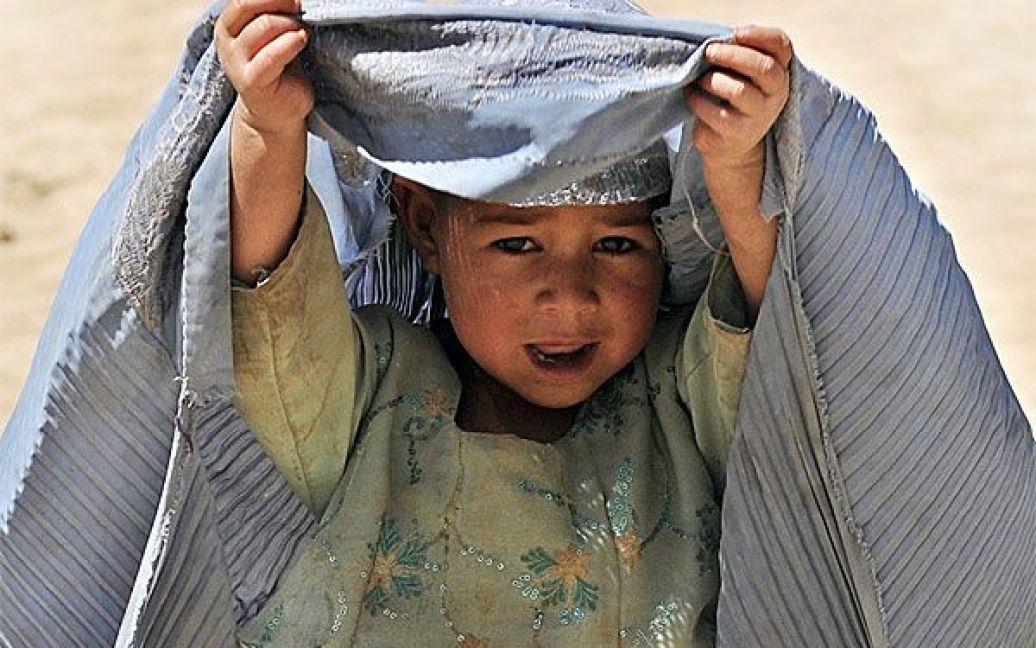 Афганістан. Афганська дівчинка-біженка у провінції Гільменд визирає з-під паранджи. ООН відзначила всесвітній день біженців. Більше 15 мільйонів чоловіків, жінок і дітей у всьому світі залишили свої домівки через військові конфлікти або гоніння. / © 