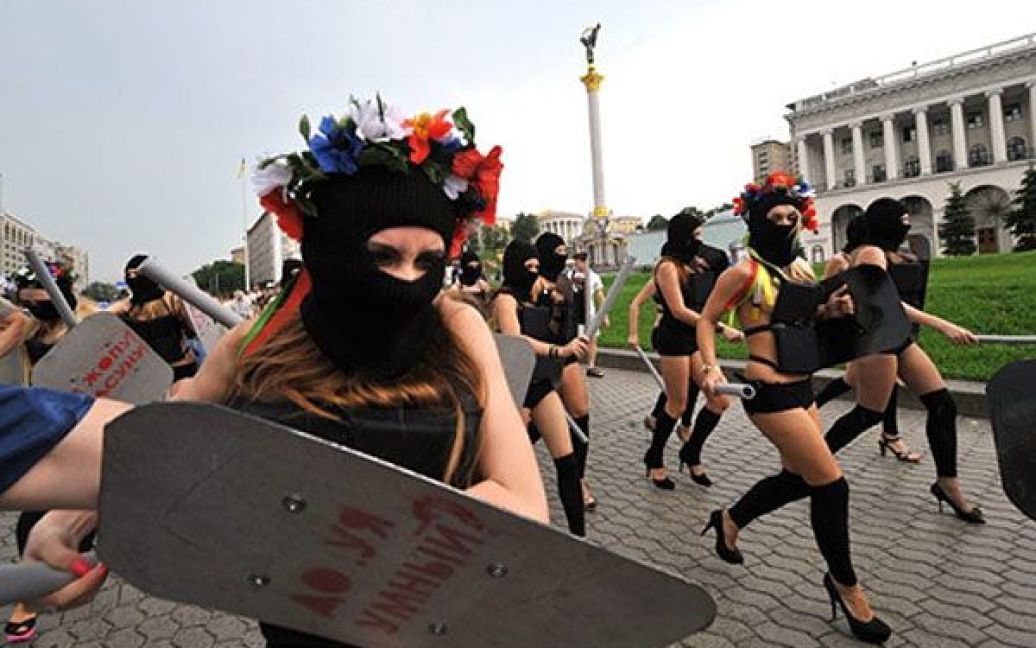 Активістки FEMEN вийшли на акцію у чорних костюмах, накшталт спецназівських, масках і з криками "Забери камеру!", "Не знімати, твою мать!" накинулися на журналістів і фотографів із поролоновими дубцями. / © AFP