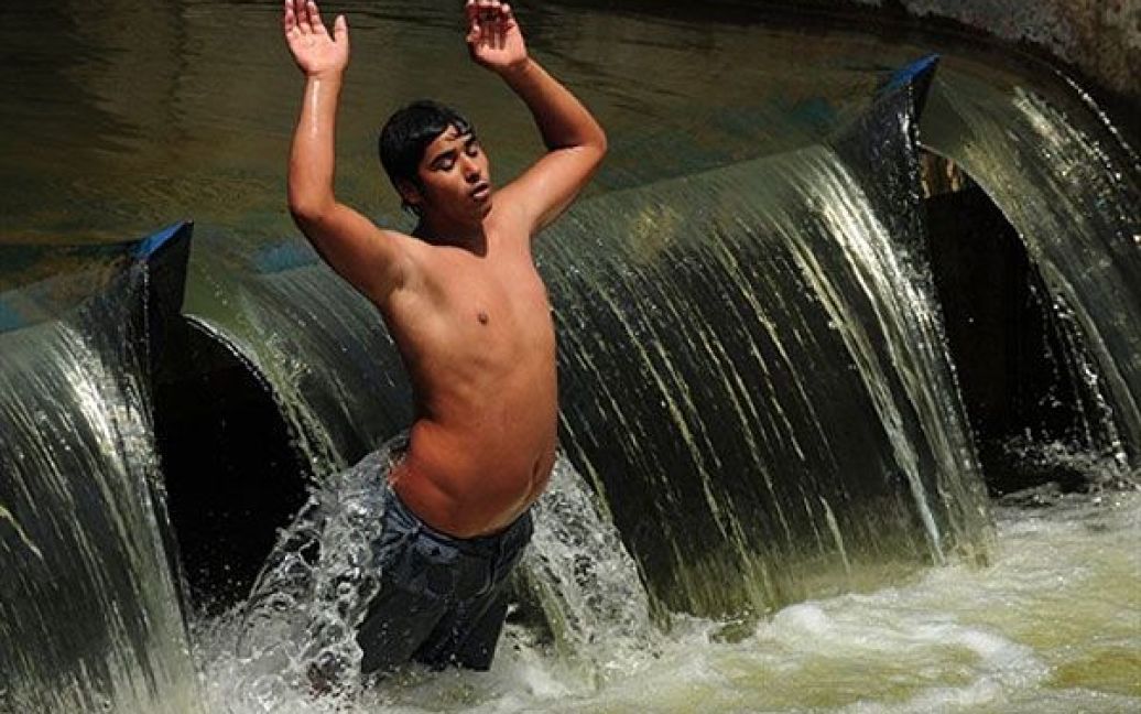 Румунія, Бухарест. Юнак купається у річці Димбовіца, в центрі Бухареста. У столиці Румунії денні температури досягли 36 градусів за Цельсієм. / © AFP