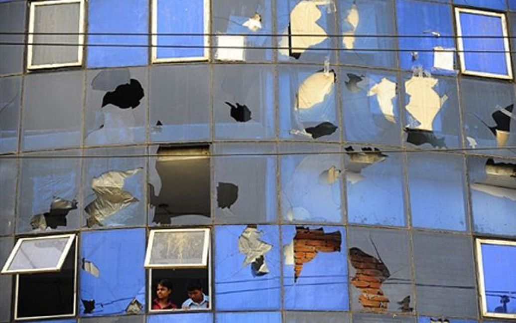 Чоловіки дивляться з вікна однієї з текстильних фабрик Дакки. Сьогодні більшість фабрик, які виробляють одяг для західних брендів, відкрилися під пильною охороною місцевої поліції після масових заворушень. Більшість співробітників цих заводів, які оголосили 19 червня страйк, сьогодні вийшли на роботу. / © AFP