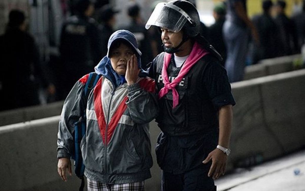 Поліцейський заспокоює жінку, члена "червоних сорочок", після сутички на окраїні Банкока. Сьогодні поліція Таїланду та солдати національної армії змусили протестувальників залишити свої барикади у діловому центрі Банкока. / © AFP