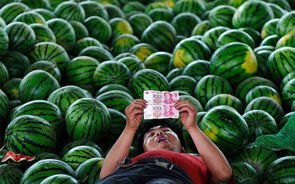 Китай, Шансі. Продавець кавунів дивиться на юані на рынку Чангжи, провінція Шаньсі. Після того, як Китай підвищив курс юаня по відношенню до долара США, вартість національної валюти Китаю досягла найвищого рівня з 2005 року. / © 