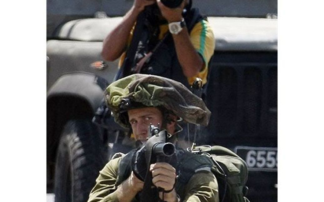 Набі Салех. Фотограф робить знімок, доки ізраїльський солдат цілиться у палестинських демонстрантів під час акції протесту проти ізраїльських поселень на Західному березі. / © AFP