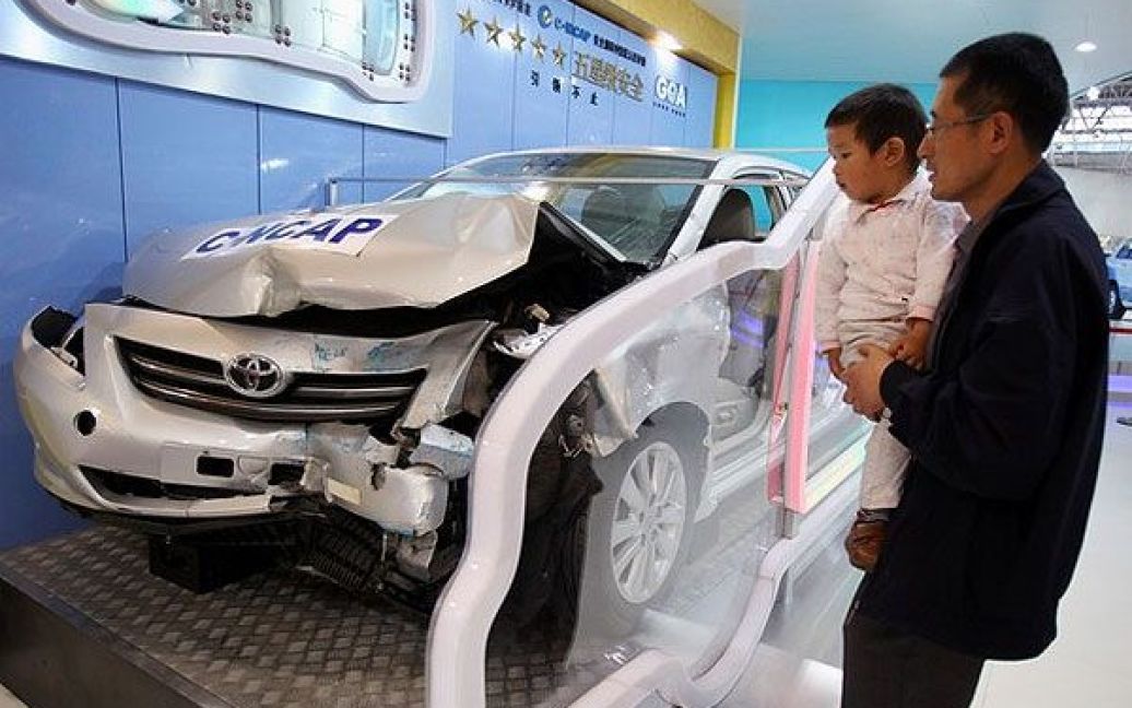 Відвідувач з дитиною роздивляються Toyota Carolla після краш-тесту. / © Getty Images/Fotobank