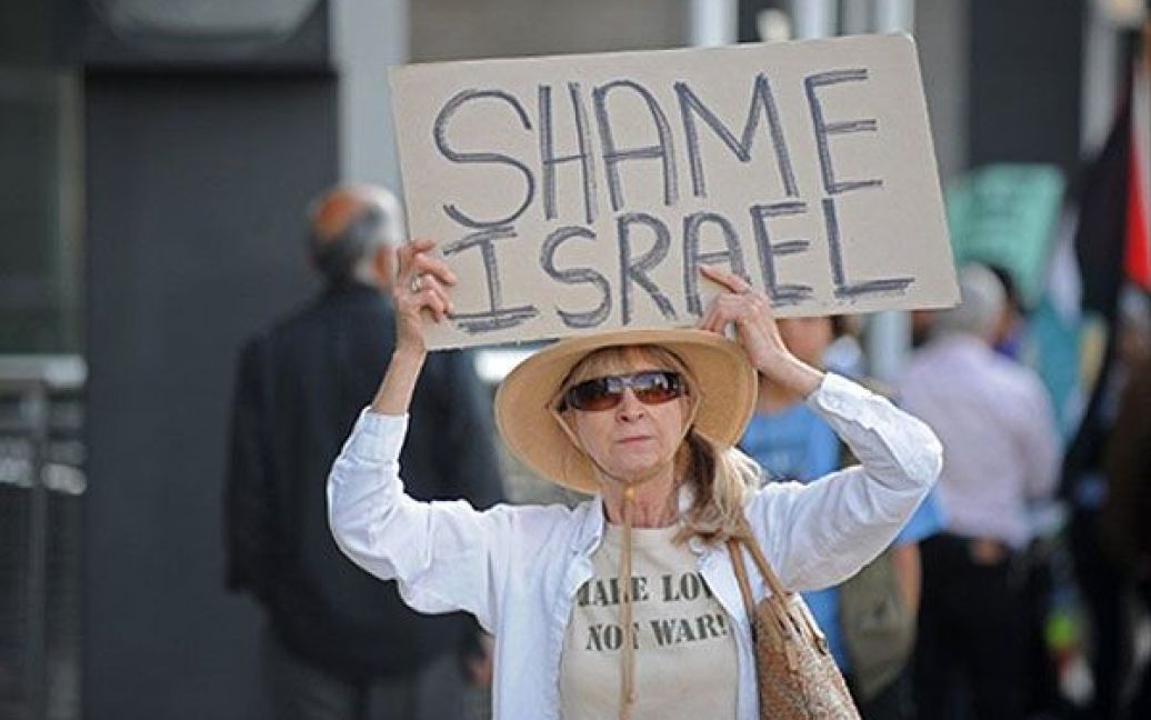 США, Лос-Анджелес. Учасниця акції протесту проти Ізраїлю перед будівлею ізраїльського конксульства у Лос-Анджелесі тримає плакат "Ганьба Ізраїлю" / © AFP