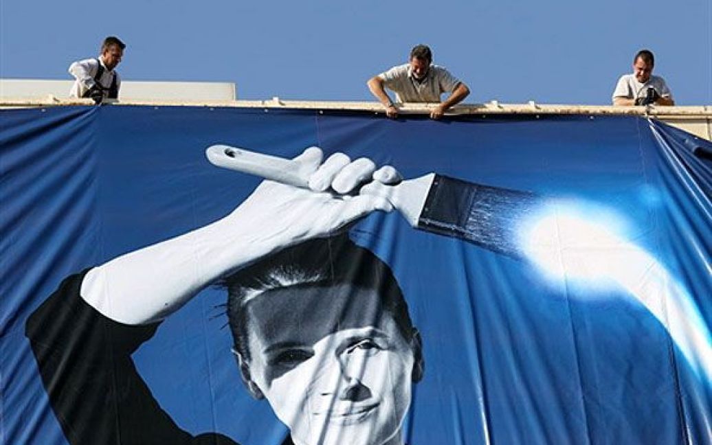 Франція, Канни. Робочі закріпляють рекламний плакат 63-го Каннського кінофестивалю на фасаді Палацу фестивалів. На плакаті зображено французьку актрису Жюльєтт Бінош. / © AFP