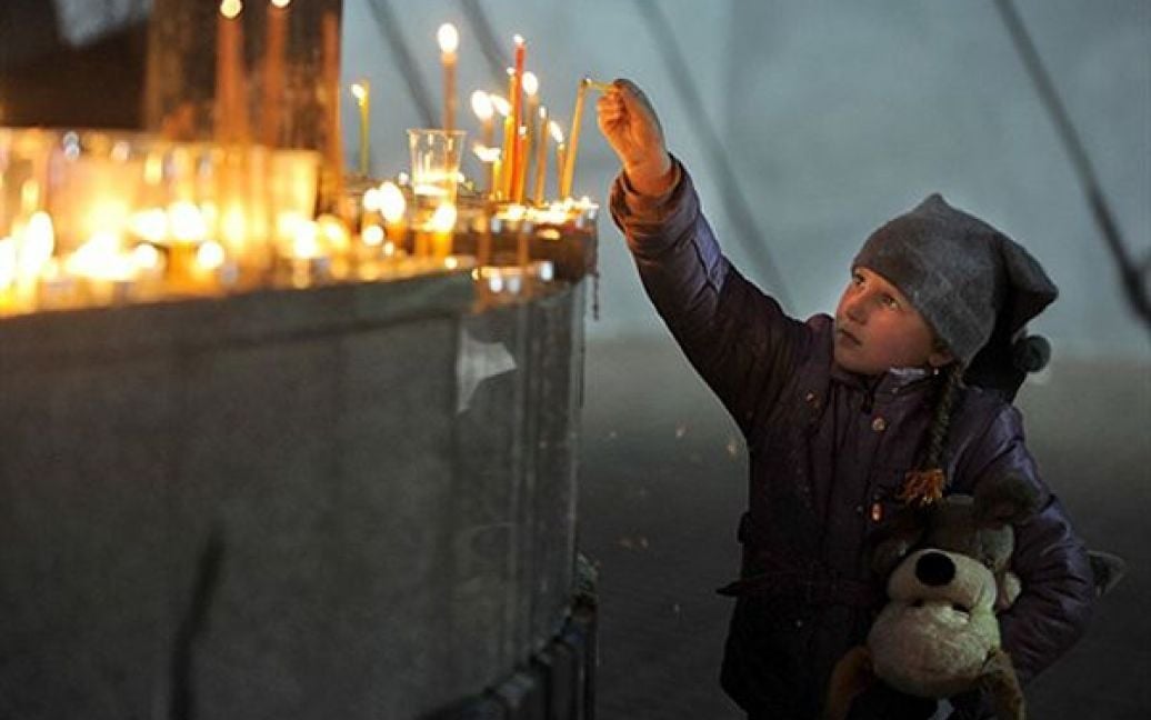 Дівчинка запалює свічку біля пам&rsquo;ятника загиблим шахтарям у Кемеровській області. В наслідок вибухів на найбільшій вугільній шахті "Распадская", найбільшої у Росії, загинули 60 шахтарів. / © AFP