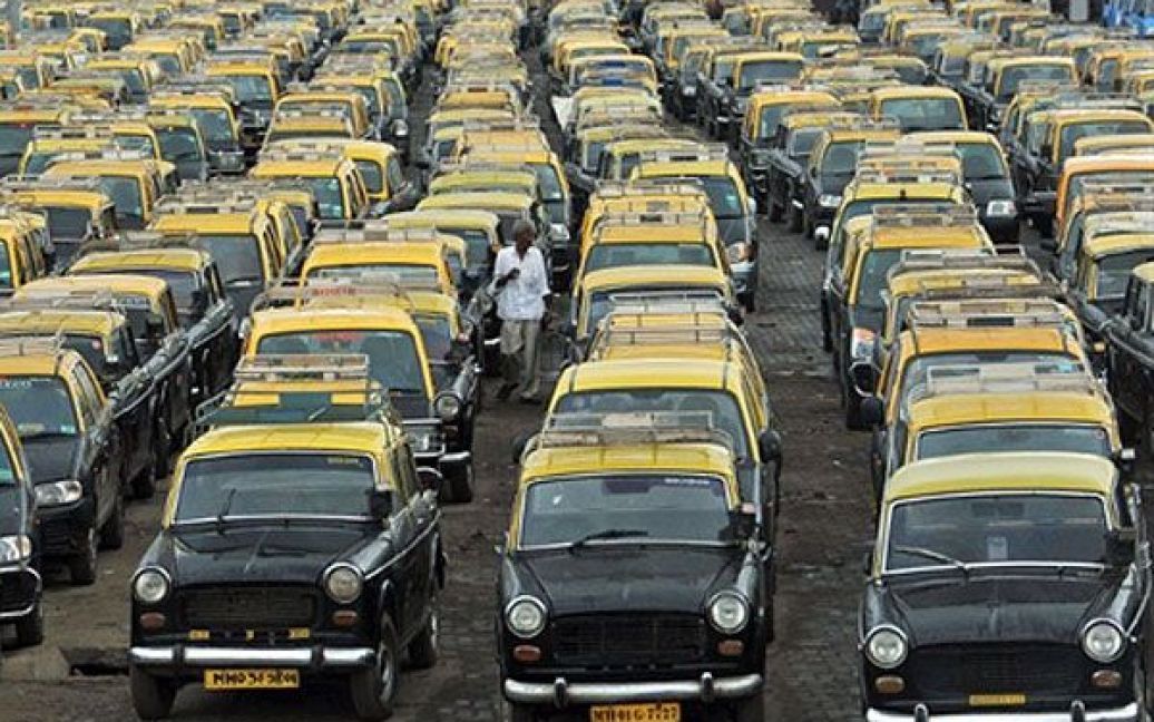 Індія, Мумбаї. Таксист ходить між припаркованих таксі у аеропорту міста Мумбаї. Майже 85 тисяч водіїв таксі та 100 тисяч авто-рікш оголосили страйк на знак протесту проти підвищення цін на природний газ. / © AFP