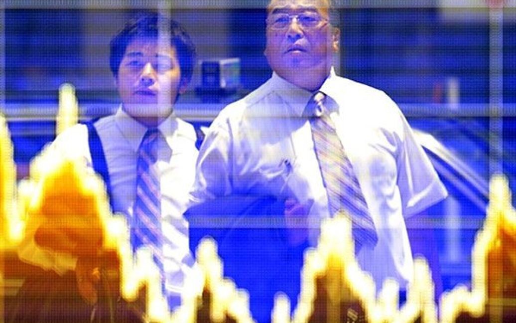 Японія, Токіо. Японські бізнесмени дивляться на табло з цінами на акції. / © AFP