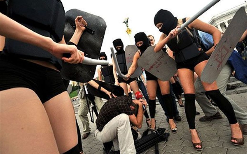 Активістки FEMEN вийшли на акцію у чорних костюмах, накшталт спецназівських, масках і з криками "Забери камеру!", "Не знімати, твою мать!" накинулися на журналістів і фотографів із поролоновими дубцями. / © AFP