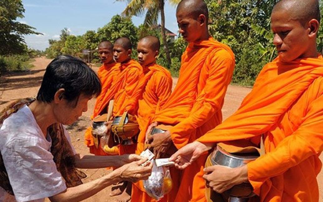 Камбоджа, Кайдани. Жінка дає подаяння буддійським ченцям на дорозі у провінції Кайдани. Камбоджа обіцяла міжнародним країнам-донорам провести різноманітні реформи і ефективно використовувати фінансову допомогу. Камбоджа, як очікується, має отримати більше мільярда доларів США від міжнародних організацій. / © AFP
