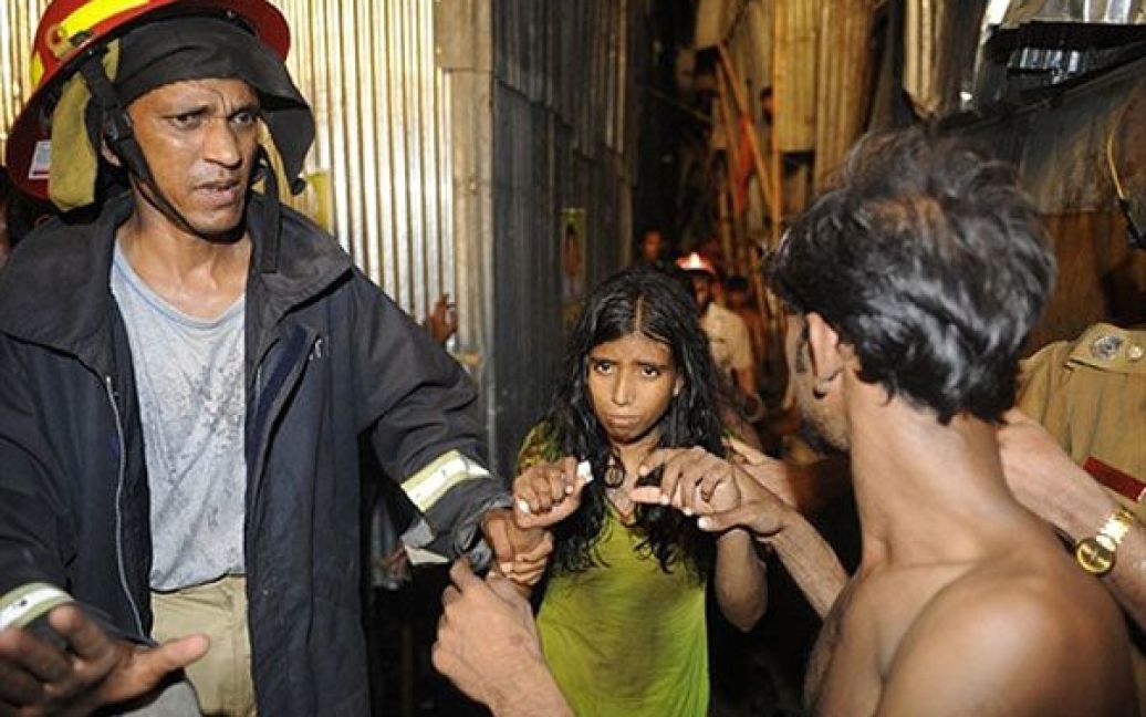 Бангладеш, Дакка. Пожежний виводить врятовану дівчинку Хену з місця трагедії. Хена змогла врятуватись після того, як пізно вночі обвалився 4-поверховий будинок. Будинок завалився на кілька халуп у нетрях Дакки. Невідома кількість людей знаходиться під завалами. На місці трагедії працюють поліція і пожежні. / © AFP