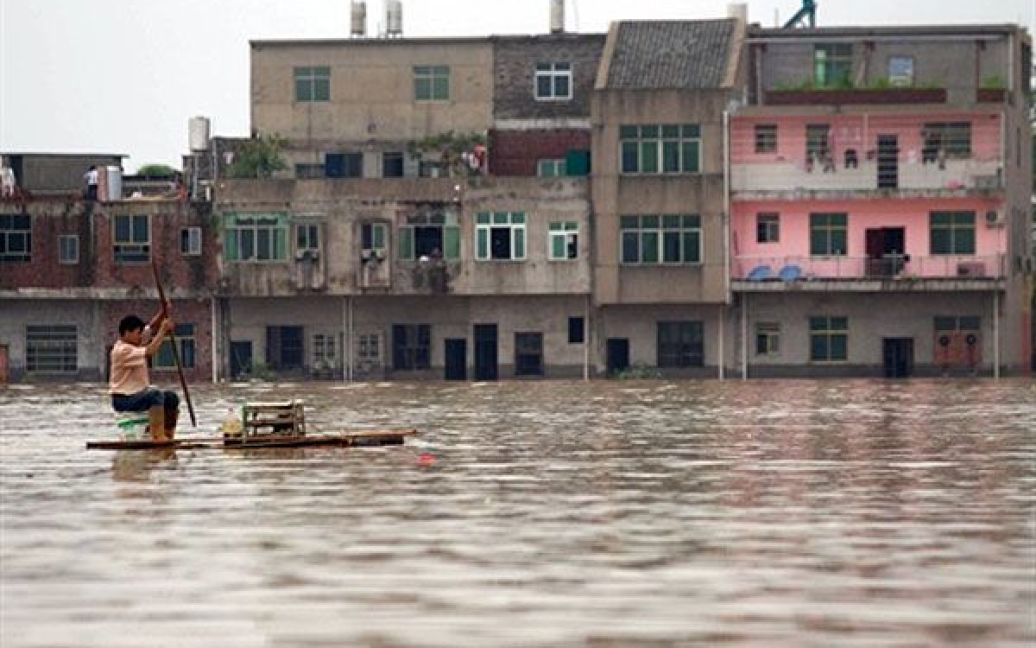 Китай, Фучжоу. Китаєць пливе на саморобному плоту затопленими вулицями міста Фучжоу у провінції Цзянсі східного Китаю. Синоптики попереджають про нові зливи, які насуваються на країну. Південна частина Китаю вже постраждала від повеней і попередніх злив, які забрали життя більше 200 людей. / © AFP