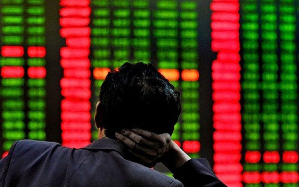 Китай, Шанхай. Китайський інвестор роздивляється монітори, які показують фондові індекси на біржі у Шанхаї. Азіатські ринки на початку торгів впали, але уповільнення падіння економіки Китаю народило сподівання, щодо поступового відновлення глобальної економіки. / © AFP