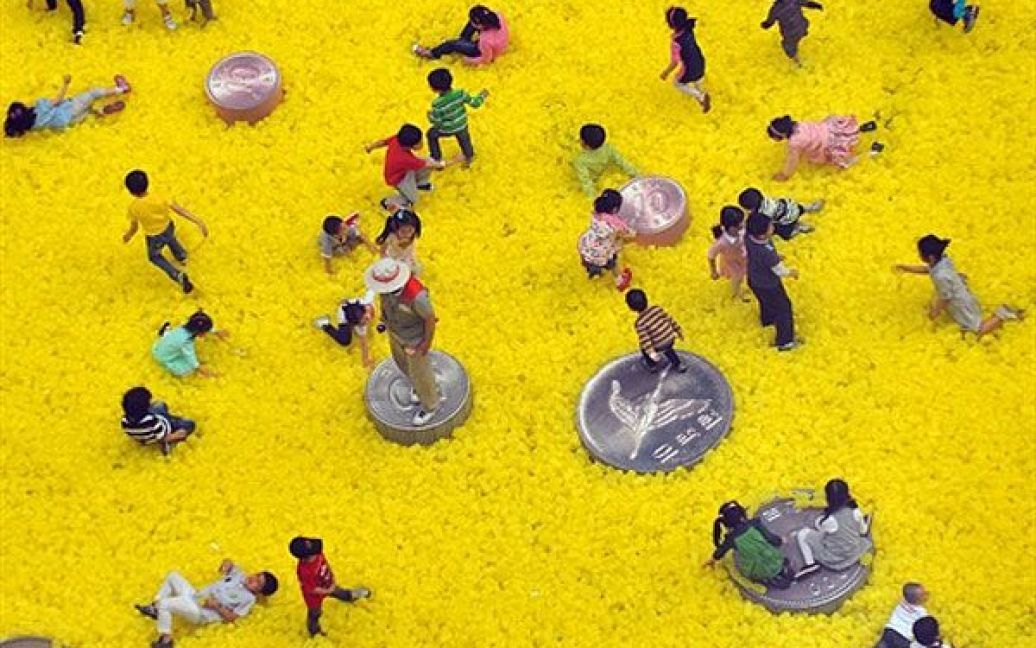 Південна Корея, Сеул. Діти грають на полі, зібраному з великих пластикових монет і мішків від грошей. Цього року зростання у економіці Південної Кореї виявилось швидшим, ніж очікувалось: 1,8% відсотка у першому кварталі завдяки активній експортній діяльності та підвищенню внутрішнього попиту. / © AFP