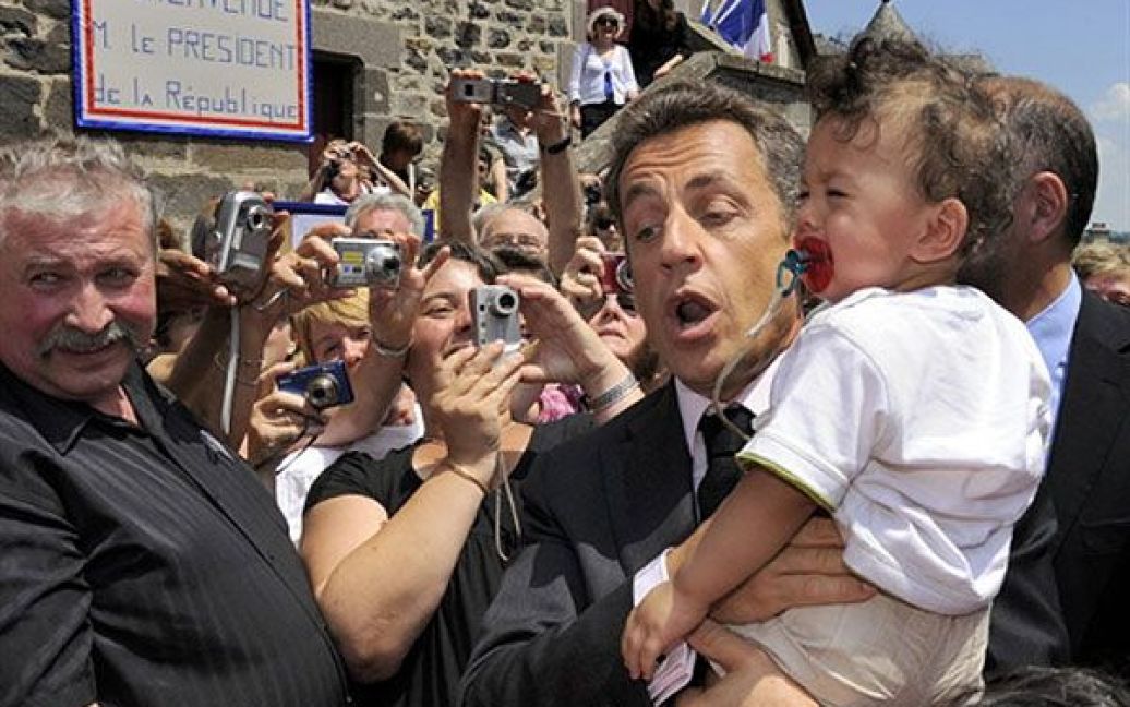 Франція, Мур-де-Барре. Президент Франції Ніколя Саркозі намагається заспокоїти дитину, яку він тримає на руках, під час візиту до Мур-де-Барре, центральна Франція. Рейтинг довіри Ніколя Саркозі впав до 26 відсотків, це найнижчий рівень з того часу, коли Саркозі зайняв свою посаду три роки тому. / © AFP