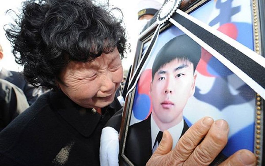 Жінка цілує портрет свого сина під час церемонії похорону корейських моряків, які загинули під час вибуху військового катеру кілька днів тому. Уряд Кореї підозрює КНДР у підриві катера, оскільки він патрулював прикордонну територію. / © AFP