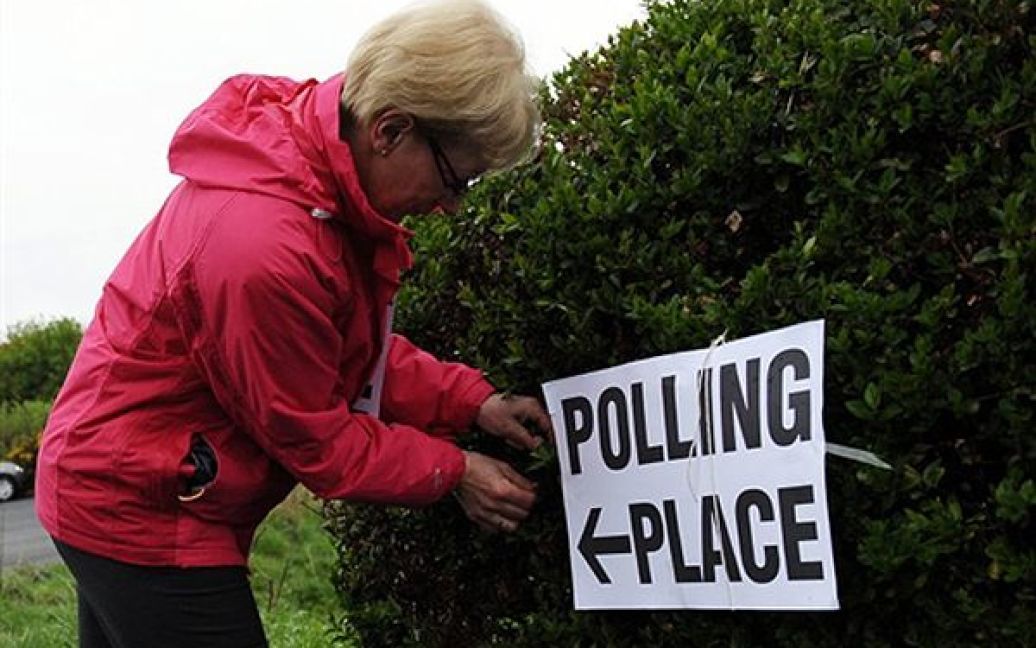 Жінка лагодить табличку виборчої дільниці у Куінсберрі, Шотландія. Сьогодні у Сполученому королівстві відбулися парламентські вибори. / © AFP