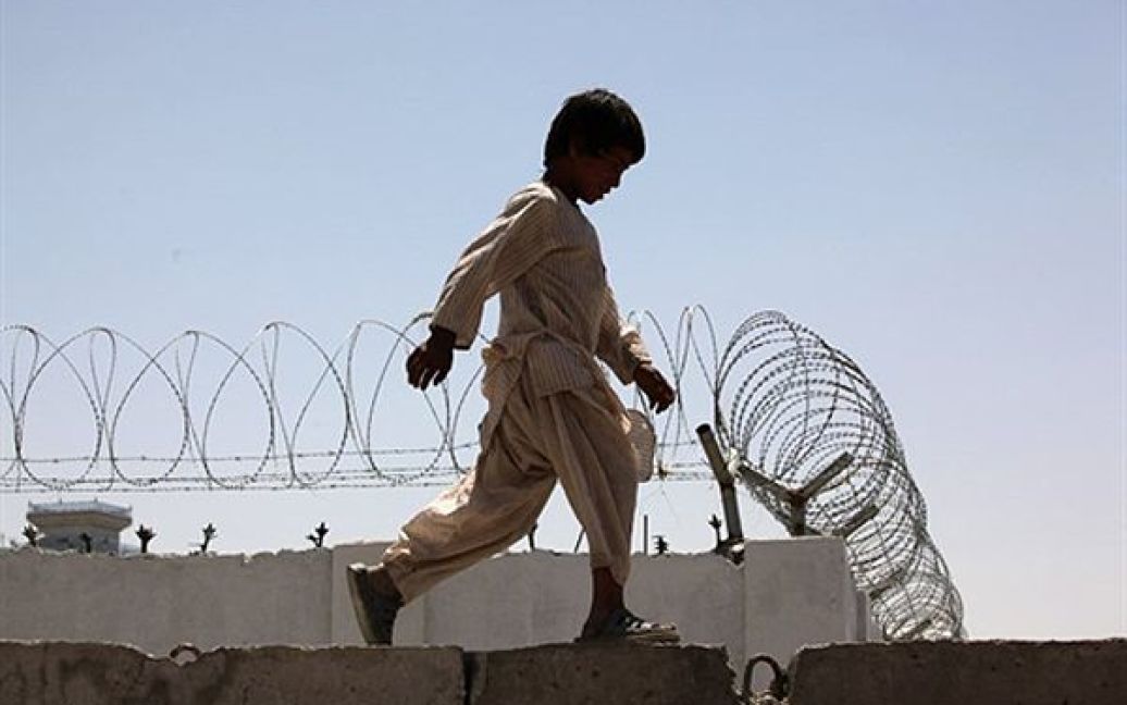 Хлопчик гуляє вздовж стіни міської в&rsquo;язниці у Кандагарі. НАТО звинуватило Талібан за скоєння теракту на весіллі. 9 червня терорист-смертник підірвав себе на весіллі у Кандагарі, на якому були присутні солдати афганської армії. В наслідок теракту загинули щонайменше 40 людей. / © AFP