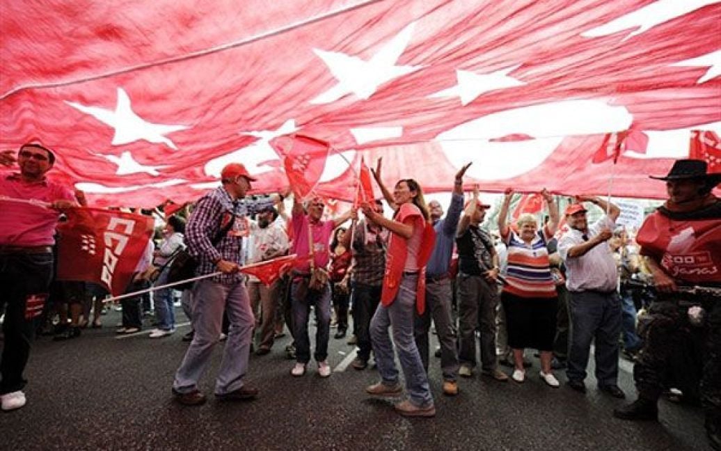 Іспанія, Мадрид. Люди тримають в руках величезний прапор профсоюзу під час акції протесту проти економічної політики уряду та скорочень. Десятки тисяч державних працівників оголосили страйк на знак протесту проти жорсткої економії, спрямованої на скорочення дефіциту державного бюджету. Профспілки, які представляють приблизно 2,6 мільйона державних працівників, починаючи з лікарів і двірників, закликали всіх до страйку після того, як уряд оголосив, що протягом наступних двох років бюджетні витрати уріжуть ще на 15 мільярдів євро (18 мільярдів доларів США). / © AFP