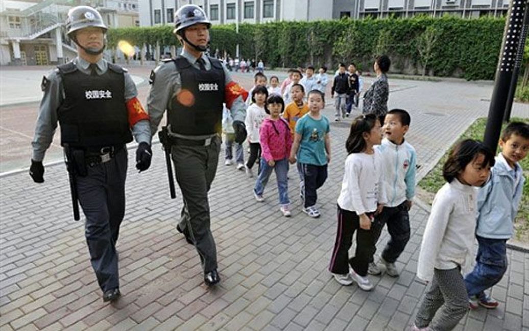 Пекін, Китай. Охорона у бронежилетах, озброєна палицями і електрошок ерами, супроводжує дітей до початкової школи у Пекіні. Поліцейське керівництво Китаю пообіцяло "серйозно відповісти" кожному, хто спробує напасти на школу. Проотягом кількох останніх тижнів у Китаї було зафіксовано п&rsquo;ять випадків кривавої бійні у дитсадках і школах. / © AFP