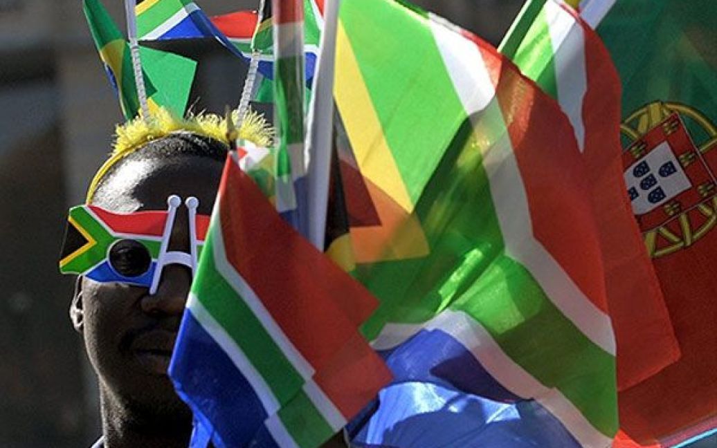 ПАР, Йоганнесбург. Вуличний торговець у окулярах кольорів південноафриканського прапору, продає сувеніри перехожим. З 11 червня по 11 липня у Йоганнесбурзі пройде Чемпіонат світу з футболу 2010, в якому беруть участь команди з 32 країн. / © AFP