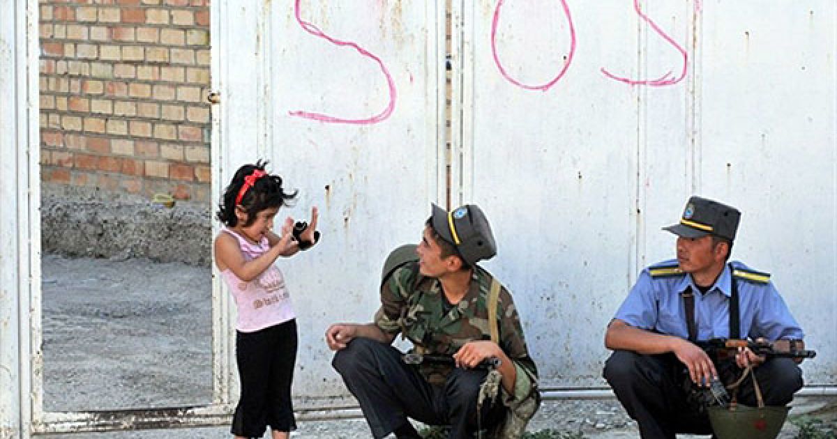 Киргизстан, Ош. Дівчинка розмовляє з киргизькими поліцейськими, які здійснюють обшук у будинках етнічних узбеків у місті Ош. Влада Киргизстану заявила, що більше половини з тих, хто втік до сусіднього Узбекистану під час кривавих міжетнічних зіткнень, повернулися до країни. / © AFP