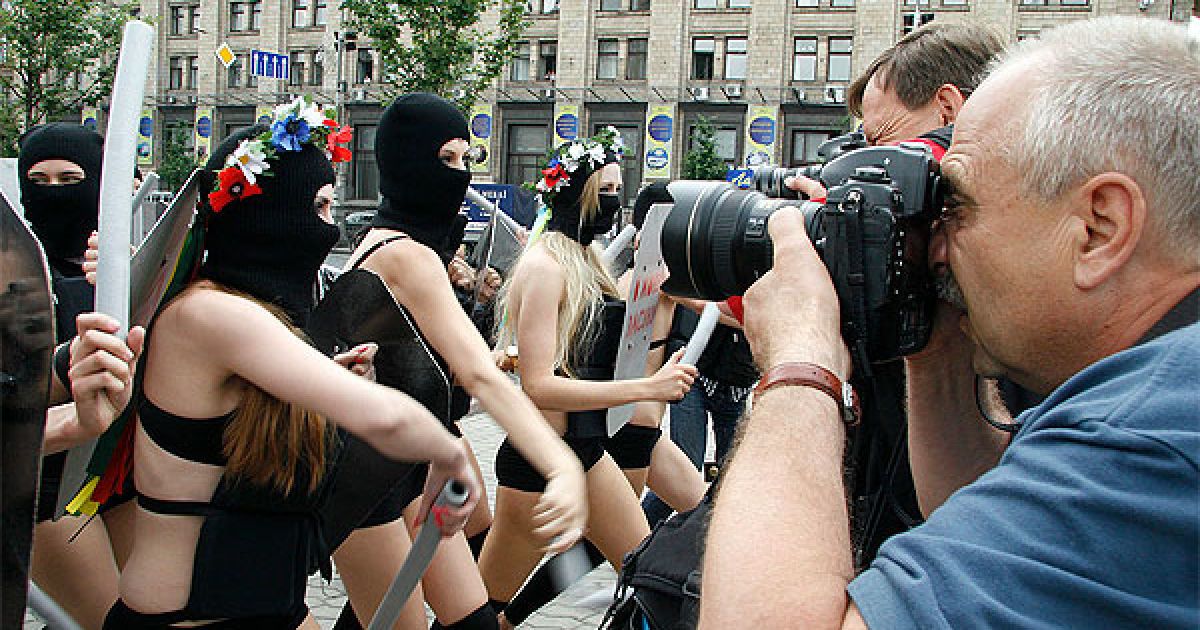Активістки FEMEN вийшли на акцію у чорних костюмах, накшталт спецназівських, масках і з криками "Забери камеру!", "Не знімати, твою мать!" накинулися на журналістів і фотографів із поролоновими дубцями. / © Жіночий рух FEMEN