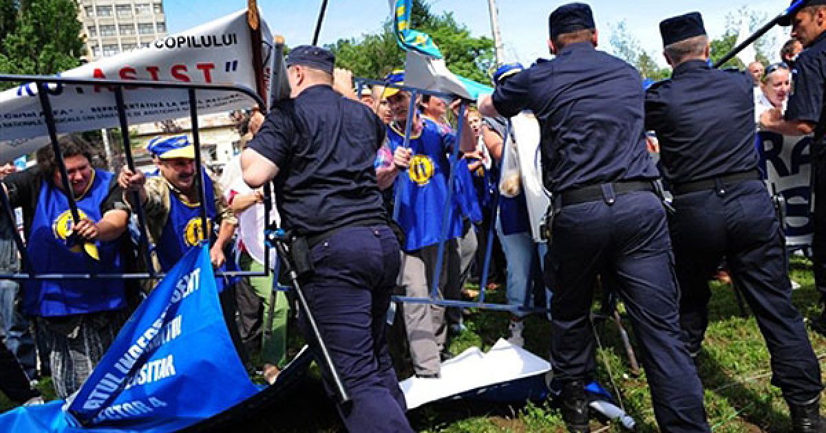 Румунія, Бухарест. Румунські поліцейські стримують натиск протестуючих біля палацу Котрочень, штаб-квартири румунського президента у Бухаресті. 
У Румунії сотні демонстрантів, незадоволені рішеннями уряду про скорочення зарплат у державному секторі на 25% і скорочення пенсій на 15%, спробували увірватися в президентський палац у Бухаресті. Натовп був розсіяний поліцією. / © AFP
