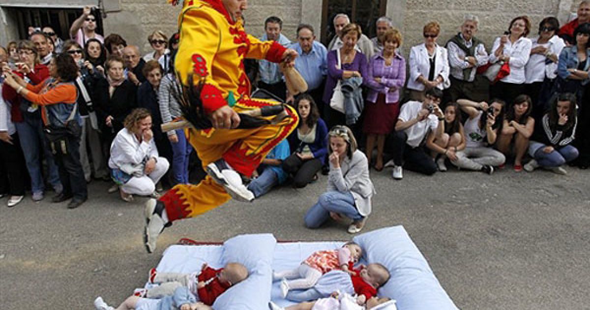 Іспанія, Кастрільо-де-Мурсія. Чоловік у костюмі чорта перестрибує через дітей, які лежать на матраці, під час ритуалу "Ель-Сальто-дель-Колахо" ("Стрибок диявола") з нагоди свята Тіла Христового. / © AFP