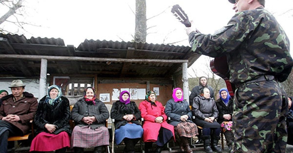 Співробітник МНС грає на гітарі для мешканців села Ільїнці. / © AFP